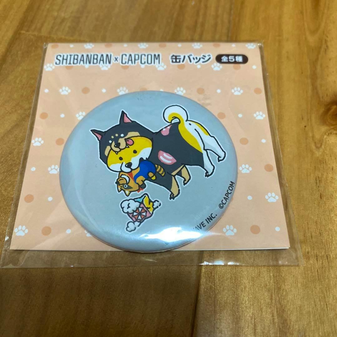 Packaged round can badge showing a Shibanban × Capcom Cerberus dog illustration on a peach paw-print backing.
