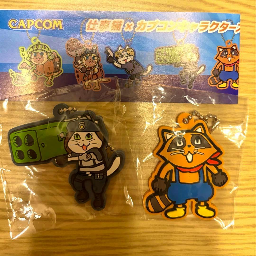 Front view of two Capcom rubber keychains in original plastic packaging with a blue header card on a wooden surface.