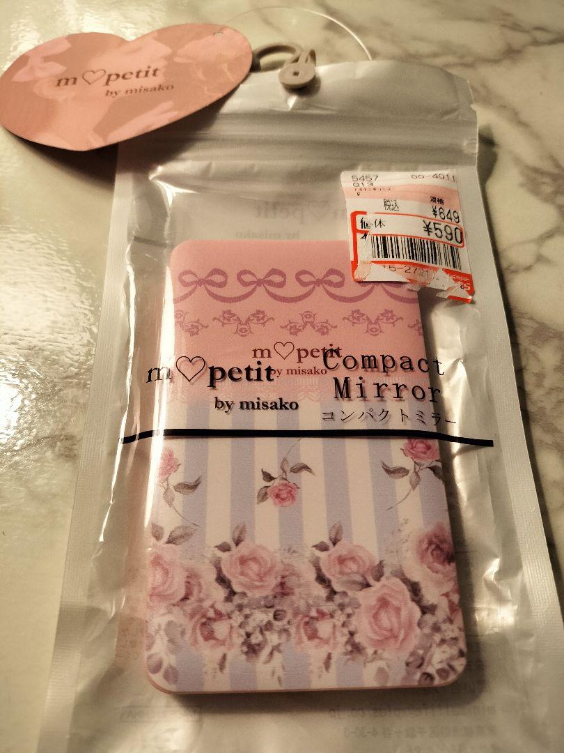 Sealed compact mirror in its retail packaging showing a pink floral-striped design and a price sticker.