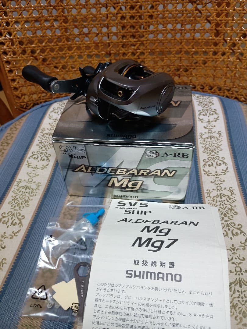 Shimano 09 Aldebaran Mg fishing reel displayed on its box with the manual and accessories visible.