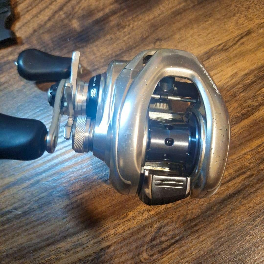 Shimano Metanium MGL HG left-hand baitcasting fishing reel on a wooden surface showing the handle and spool.