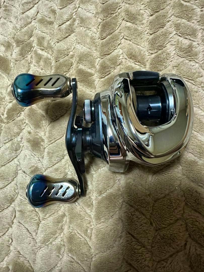 Shimano 19 Antares right-handle baitcasting fishing reel with custom Libre handle knobs shown on a textured blanket.