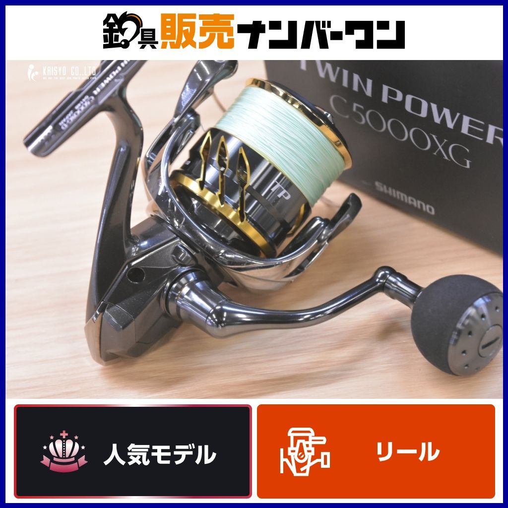 Shimano Twinpower C5000XG spinning fishing reel on a wooden surface with line spooled and the product box visible in the background.