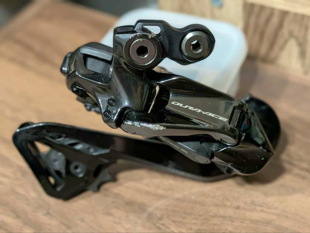Black Shimano DURA-ACE RD-R9250 rear derailleur shown on a wooden surface with visible scratches.