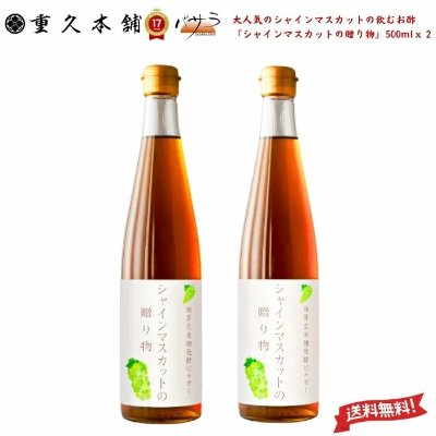 Two tall glass bottles of the シャインマスカット vinegar (500ml each) with white labels and gold caps.