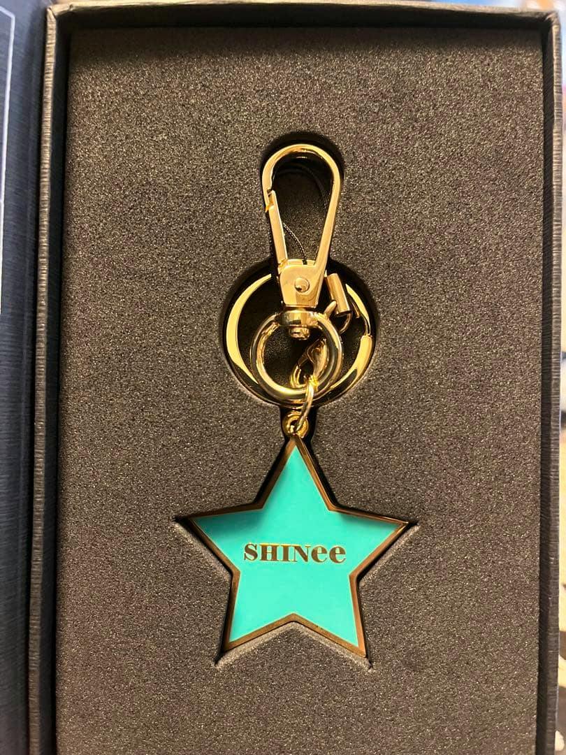 Turquoise star-shaped SHINee keychain with gold trim and clasp displayed in a foam presentation box.