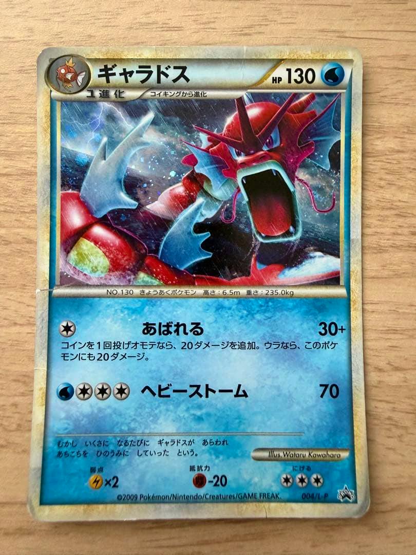 Front-view photograph of the Gyarados trading card laid on a wooden surface, showing the full card artwork and text.