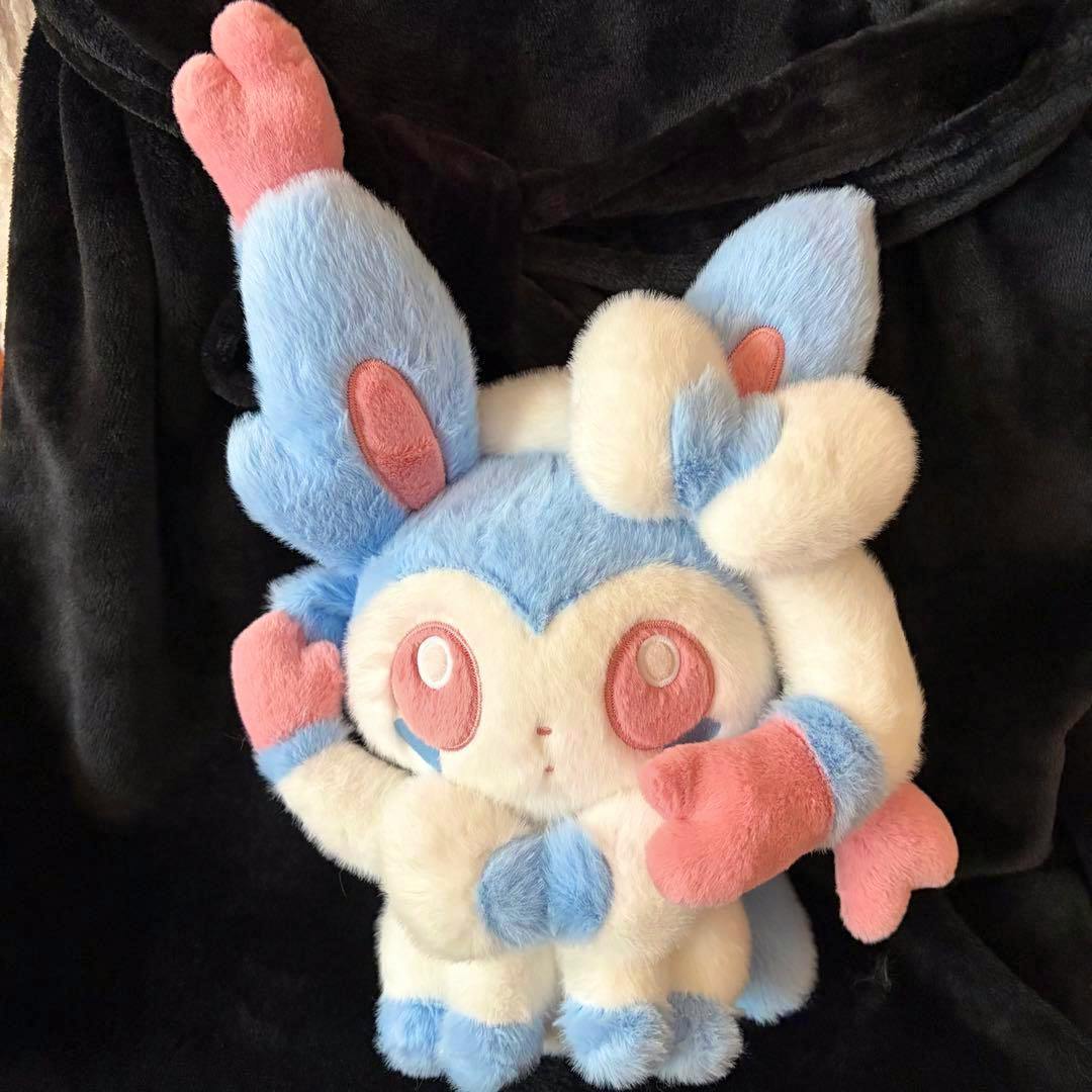 Color-variant (shiny) Sylveon plush in blue, white, and pink shown against a black background.