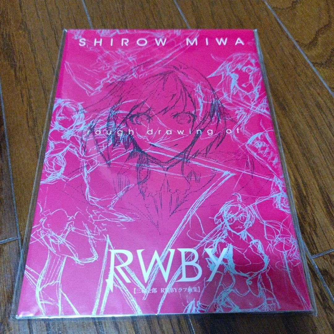 Photo of the pink front cover of the RWBY illustration book showing the title "RWBY" and white sketch-style character drawings.