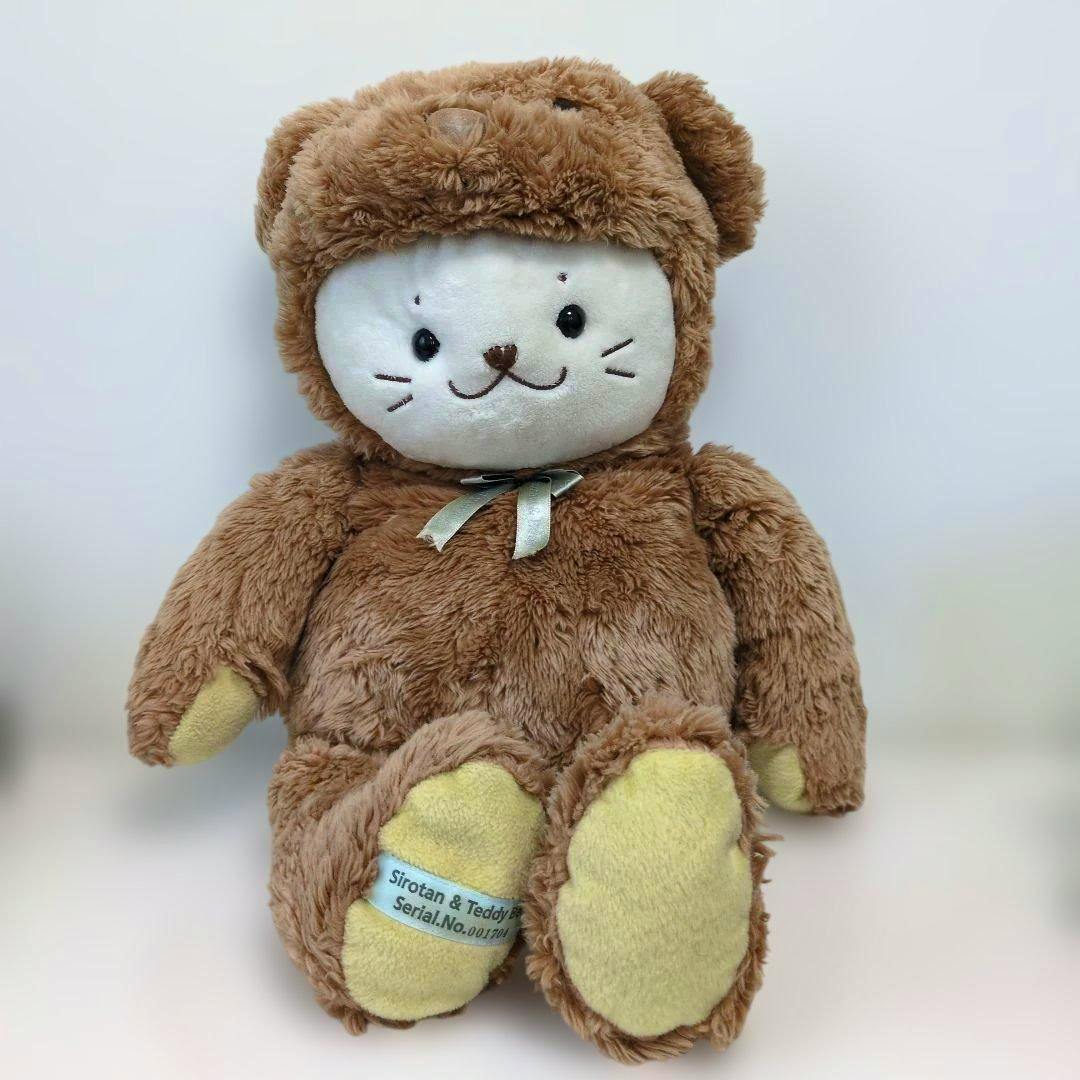 Large brown Shirotan teddy bear plush with a white face, yellow paw pads, and a ribbon, photographed against a white background.