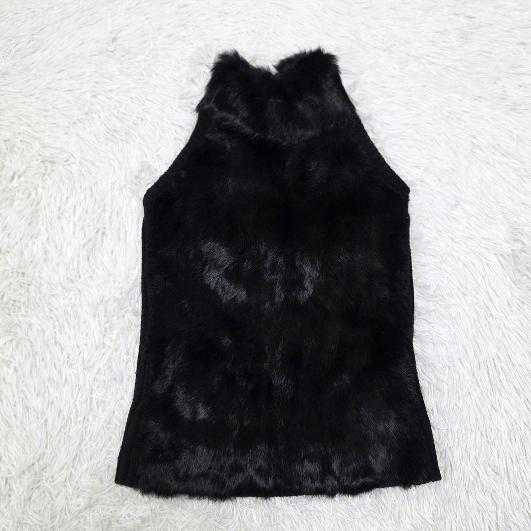Flat-lay photo of a black women's sleeveless faux-fur knit blouse laid on a white background.