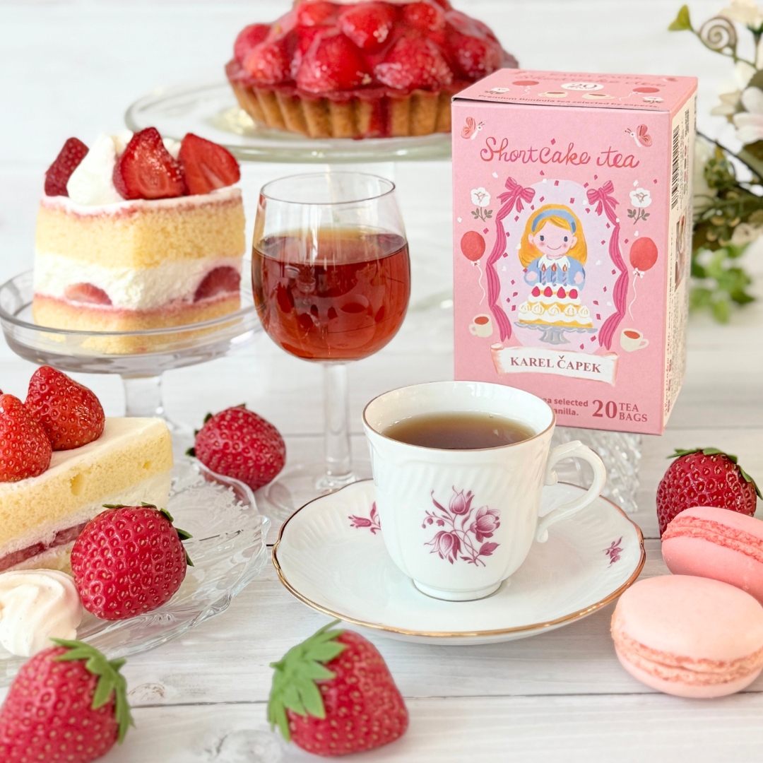 Box of Shortcake Tea (black tea bags) displayed next to a teacup, a glass of tea, strawberries, cakes, and macarons.