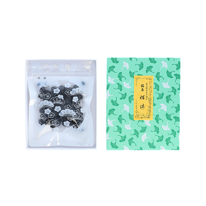 A clear resealable pouch showing black incense balls next to a green patterned box with a yellow label.