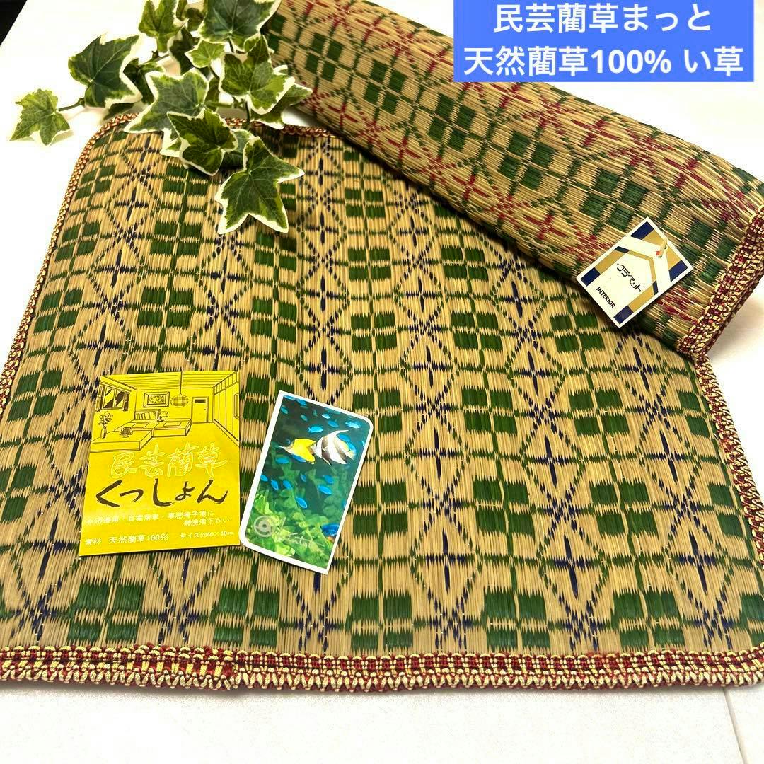 A natural igusa (straw) mat with green geometric pattern and decorative edge, partly rolled and laid flat.