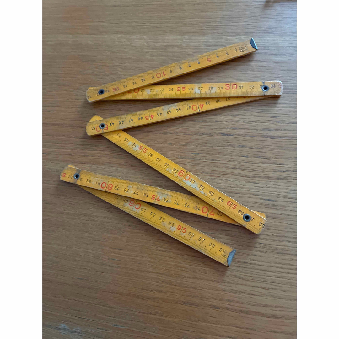 Folded wooden 1m folding ruler arranged in a zigzag on a wooden surface.