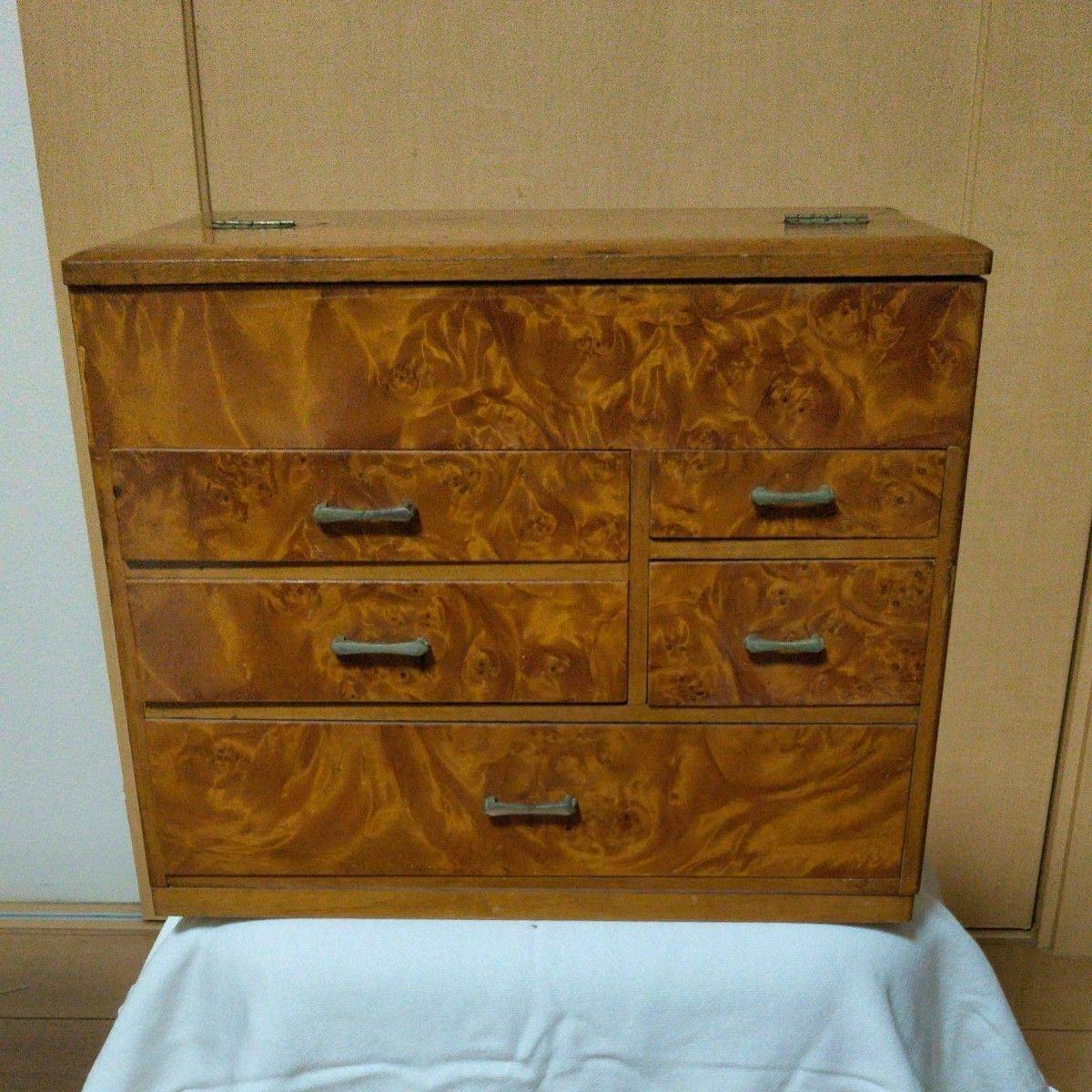 Front view of a wooden retro sewing box with five drawers and handles on a cloth-covered surface.