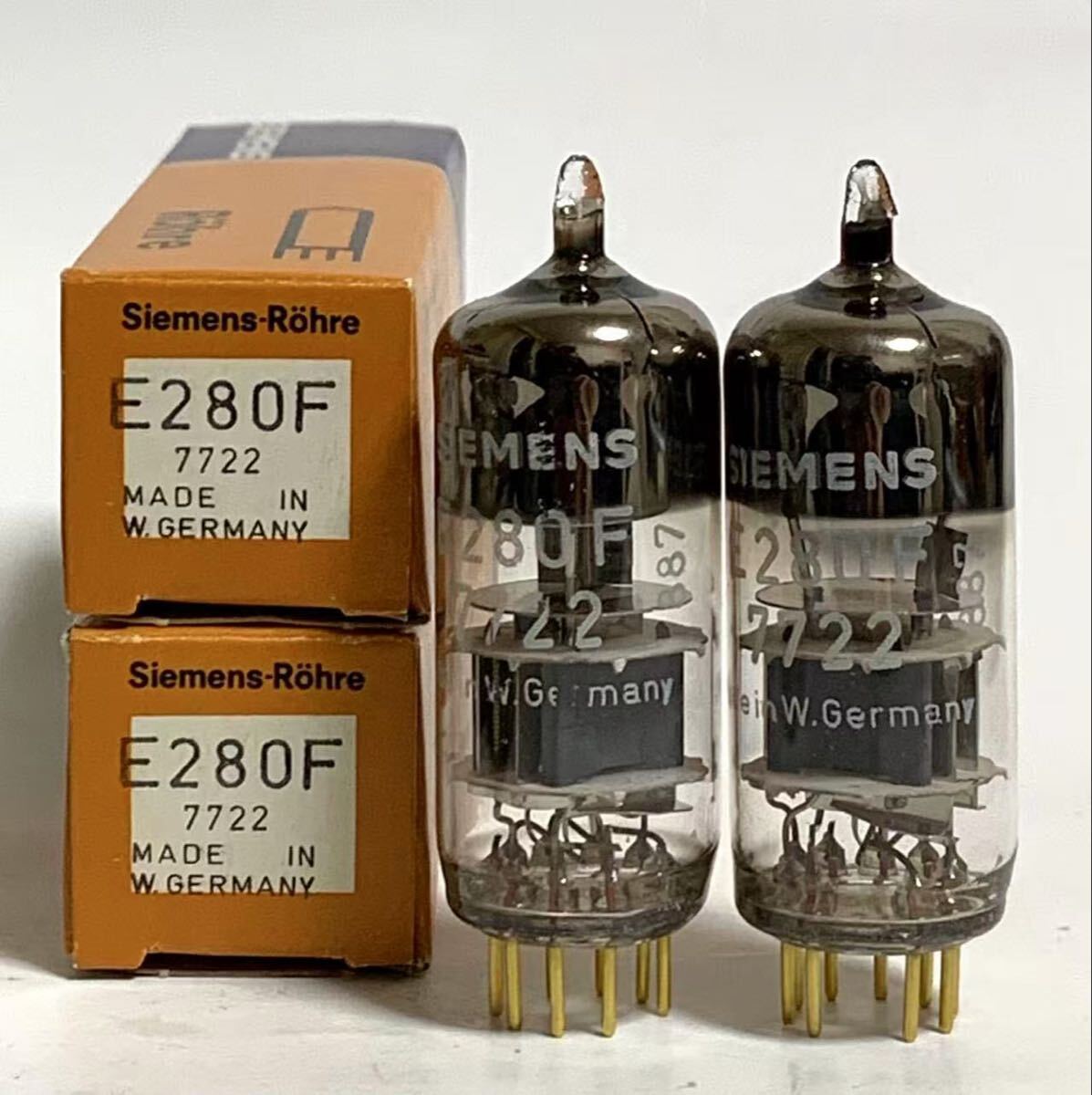 Two Siemens E280F/7722 vacuum tubes standing next to two orange Siemens-Röhre boxes.