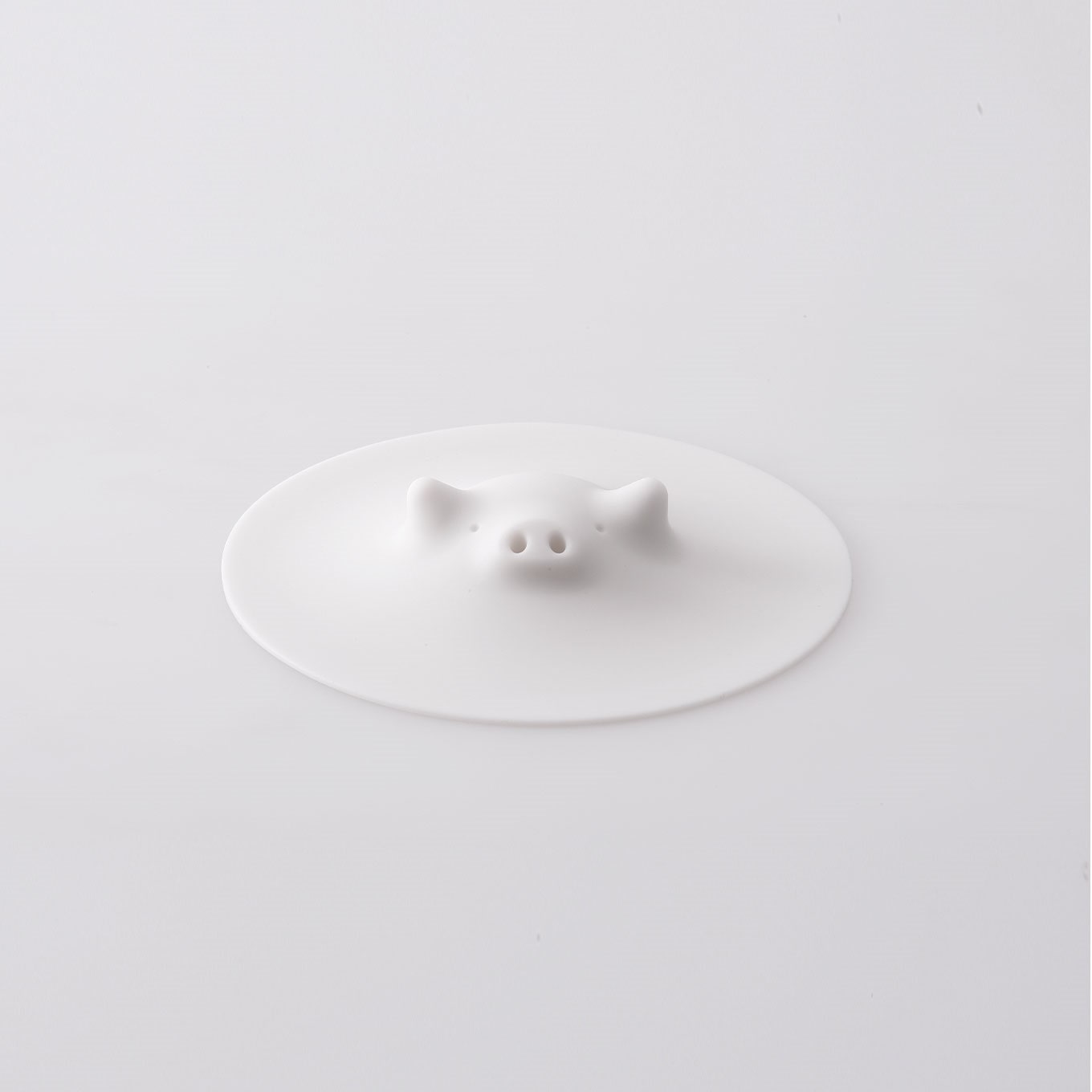 White silicone pig-shaped lid with a raised snout and ears photographed on a white background.