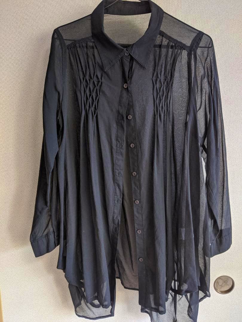 Front view of the black long-sleeve tunic blouse hanging on a hanger.