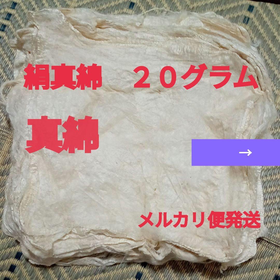 Stack of pale silk batting (絹真綿) sheets with red Japanese text overlaid.
