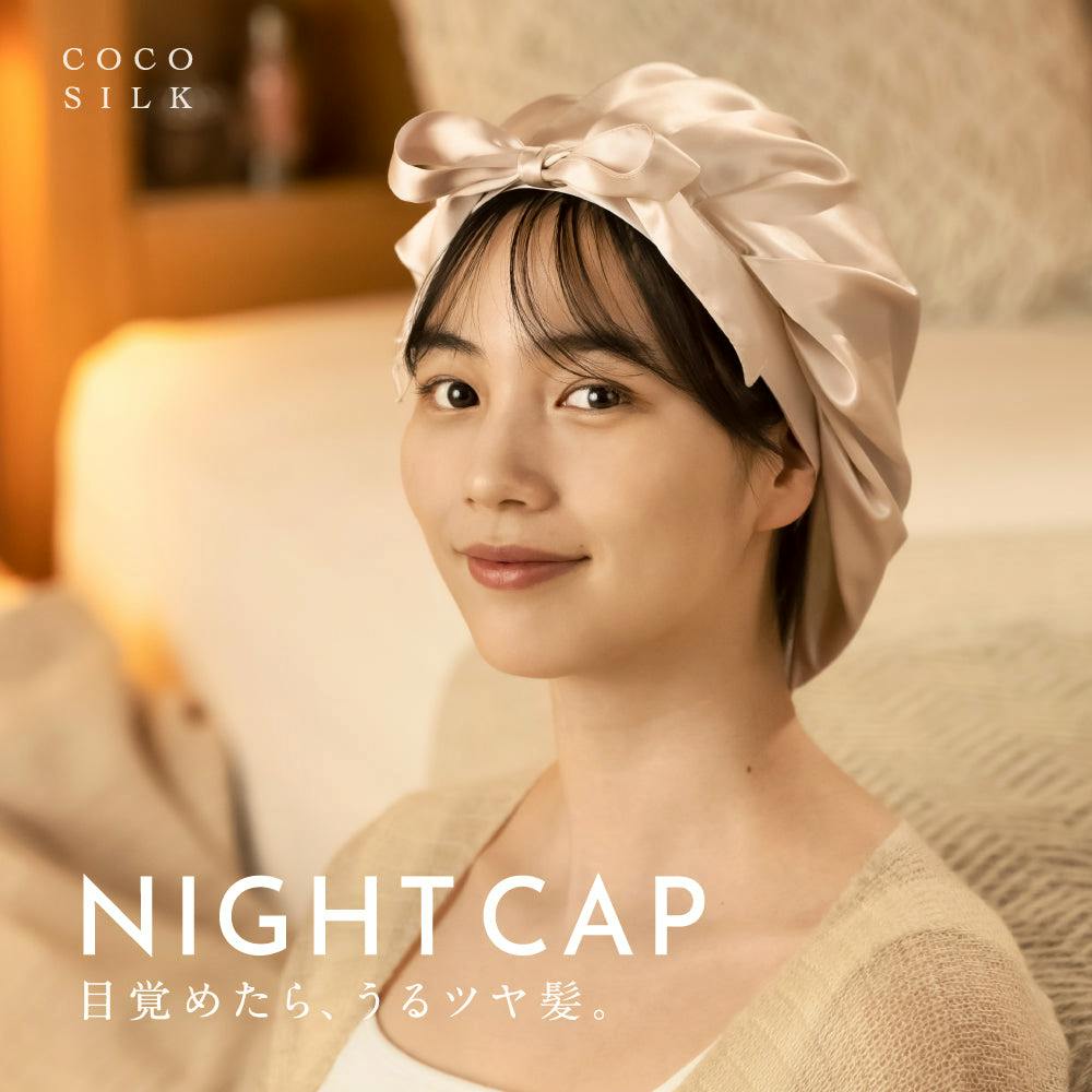 A model wearing a silk nightcap with a front-tied ribbon, shown from the shoulders up.