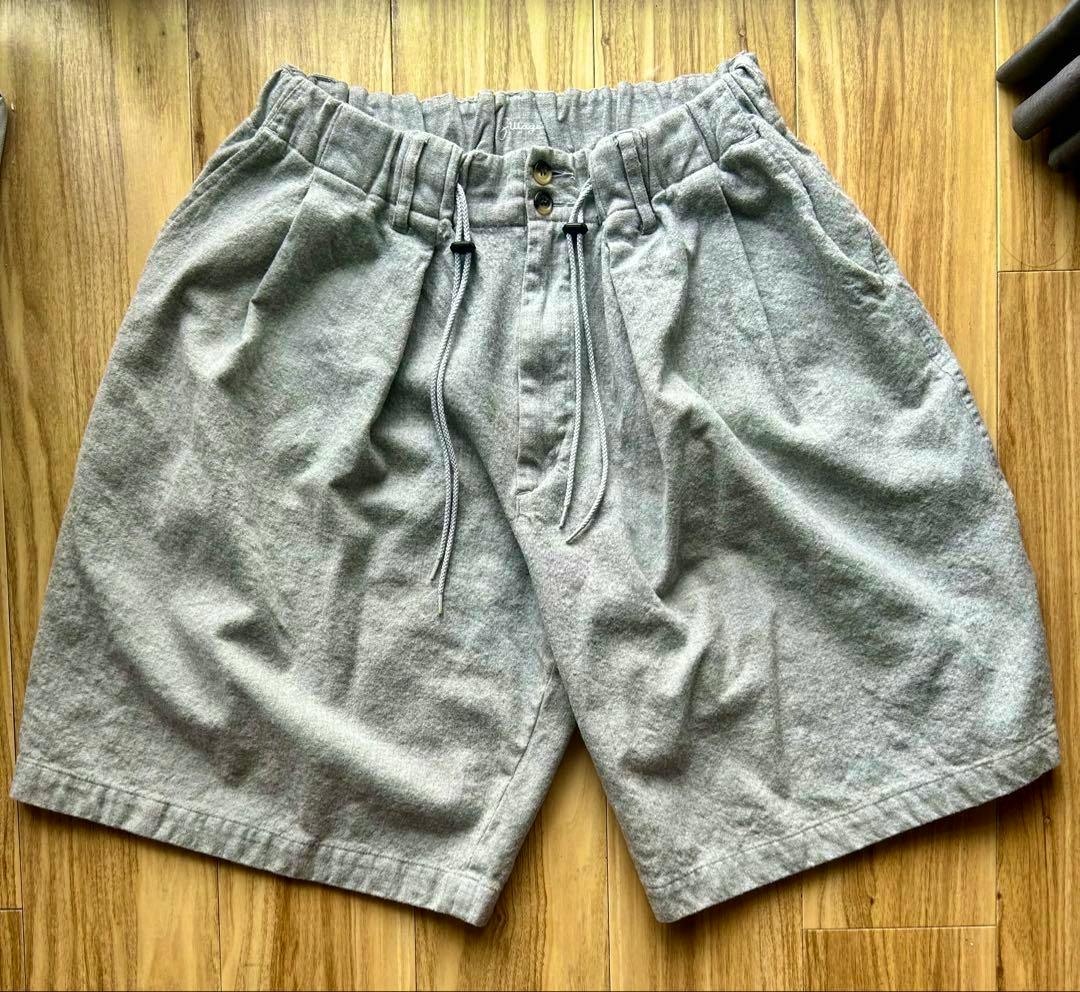 Gray men's shorts laid flat on a wooden floor showing the front and drawstring waistband.