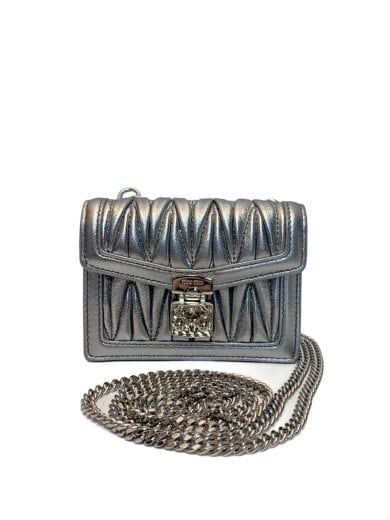 Front view of a silver cow leather bag with a quilted front panel and a metal chain strap coiled in front.