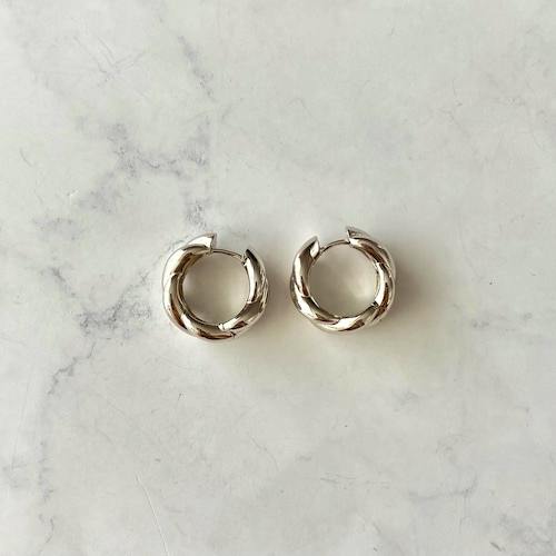 Pair of silver hoop earrings with a twisted design displayed on a light marble surface.