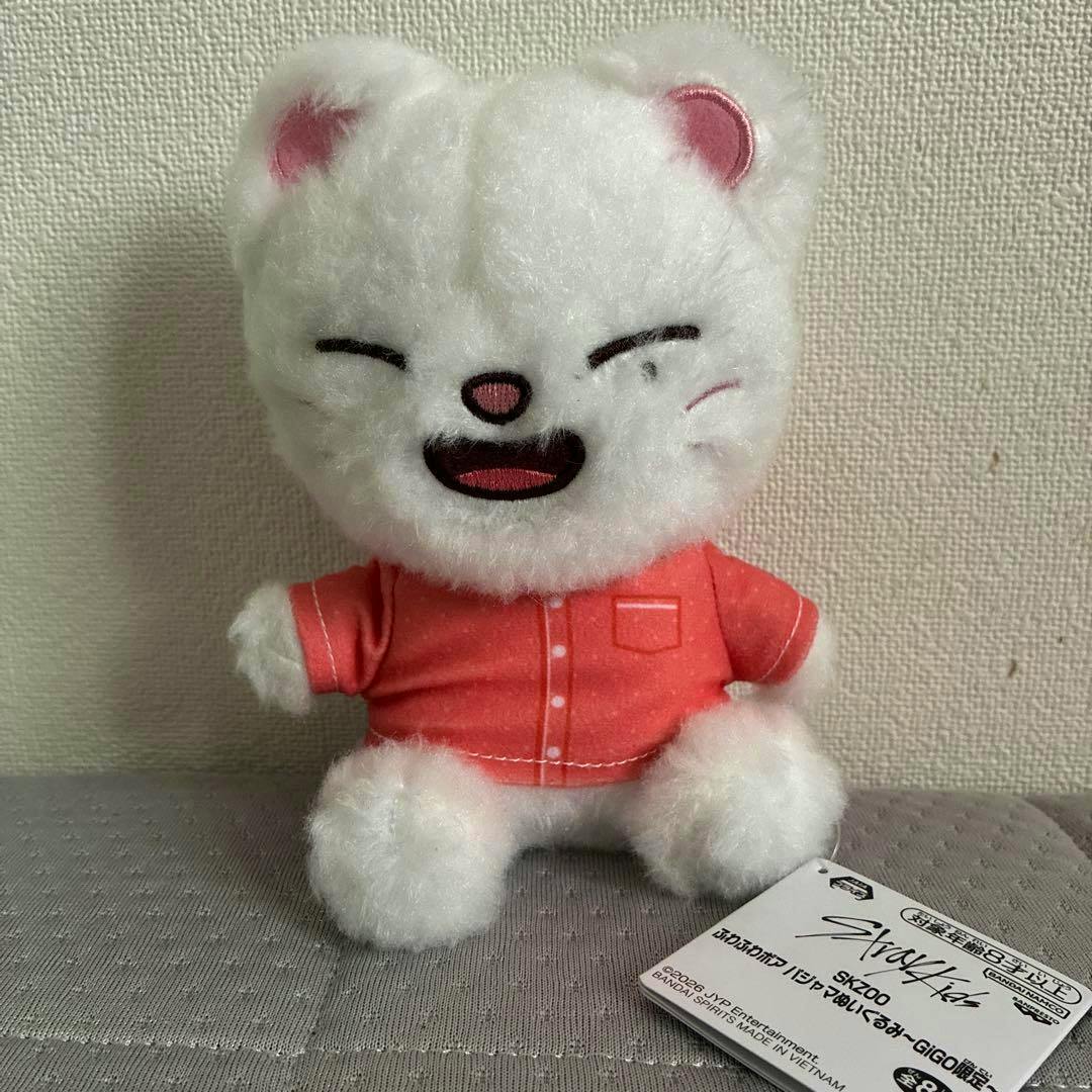 A white SKZOO fluffy plush wearing pink pajamas sits upright with its tag visible at the lower right.