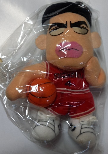 Front view of a red-uniform plush key holder doll in a plastic bag holding a small basketball.