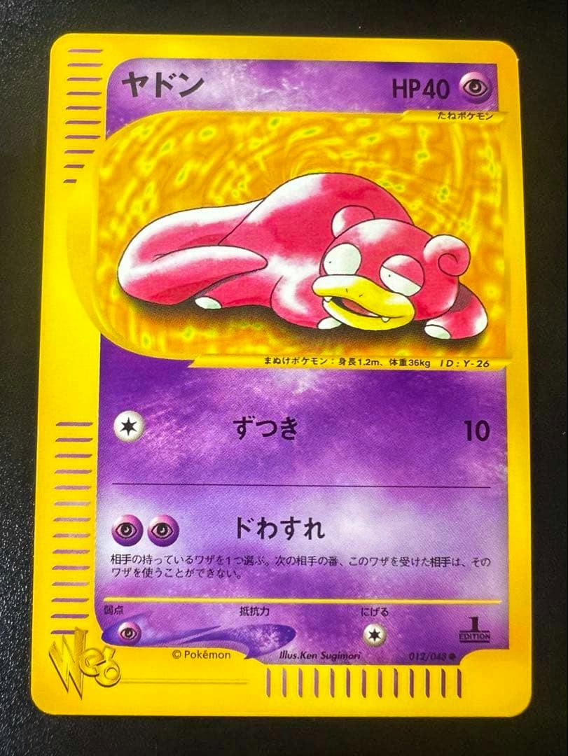 Front photo of a Japanese Pokémon trading card ヤドン (Slowpoke) with a yellow border, purple artwork area, and card number 012/048.
