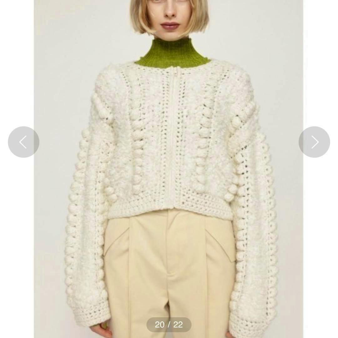 Front view of an ivory knit cardigan with textured bobble stitching shown on a model wearing beige pants.