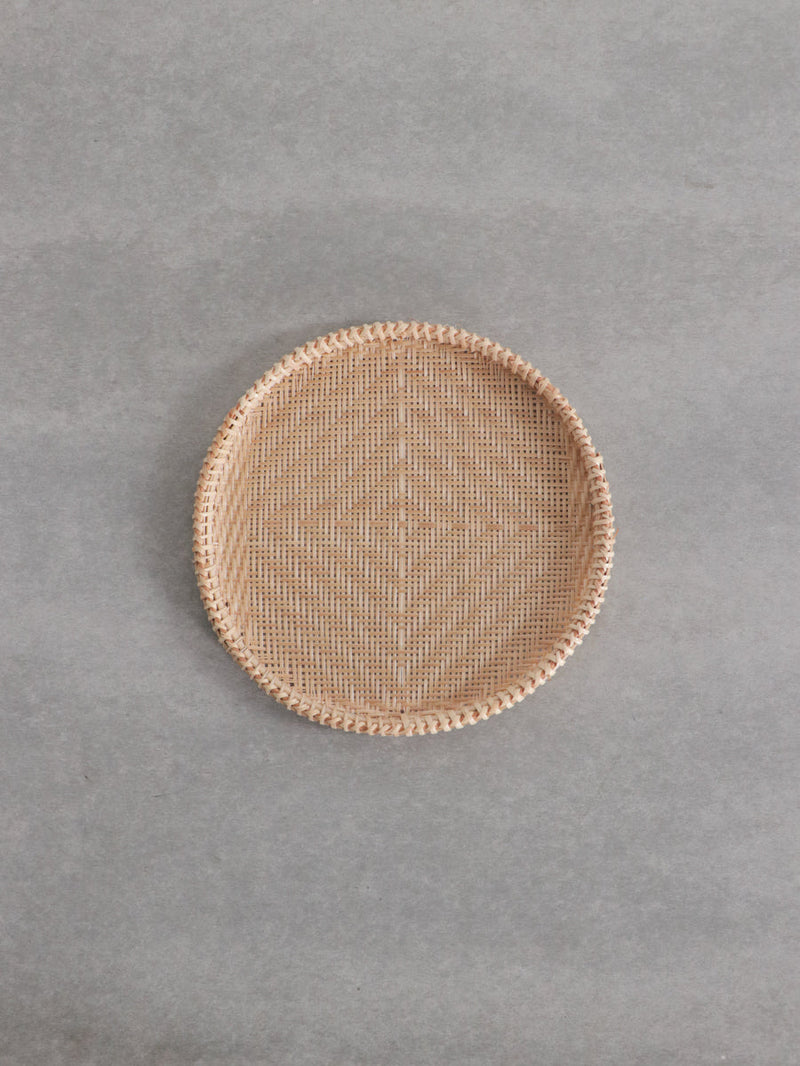 Top-down photo of the small Vietnamese bamboo strainer on a gray background.