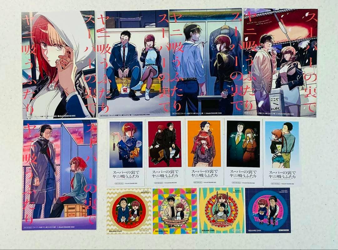 Top-down photo of the photocard set for 'スーパーの裏でヤニ吸うふたり' showing multiple illustrated photocards and colorful square stickers arranged on a white background.