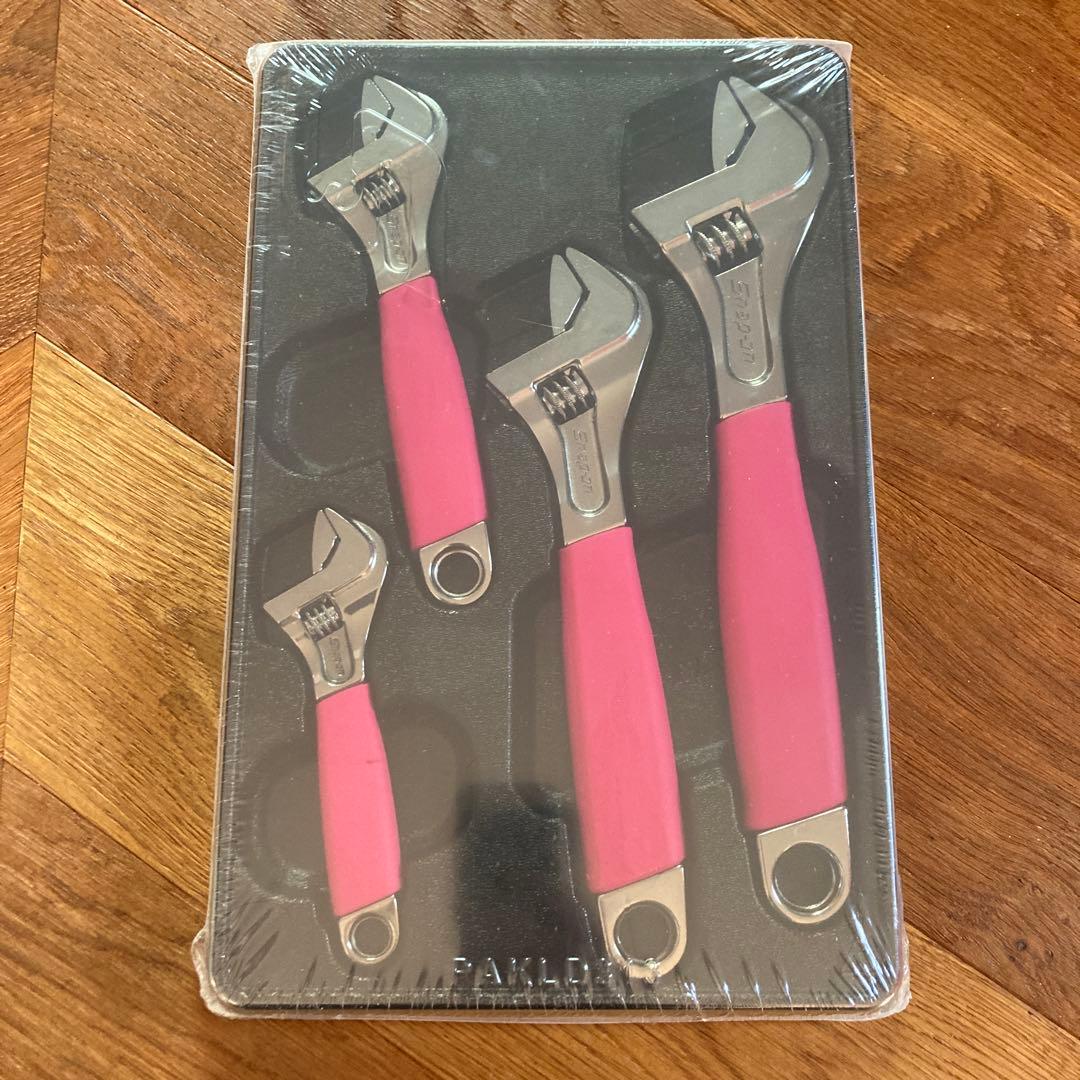 Four pink-handled adjustable wrenches arranged in a black molded tray inside shrink-wrapped packaging.