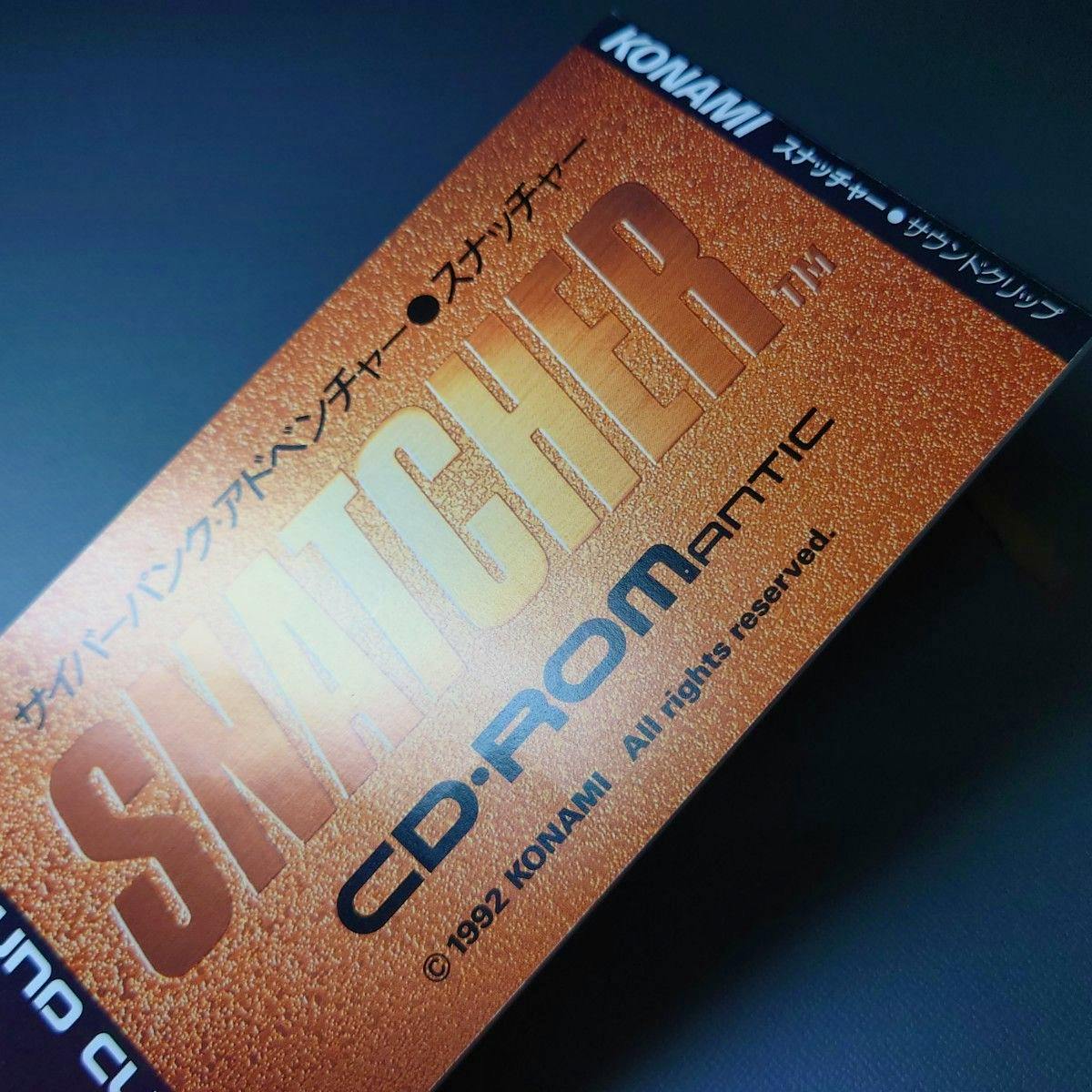 Close-up photo of the orange textured SNATCHER CD-ROM サウンドクリップ cover showing KONAMI and CD-ROMATIC text.