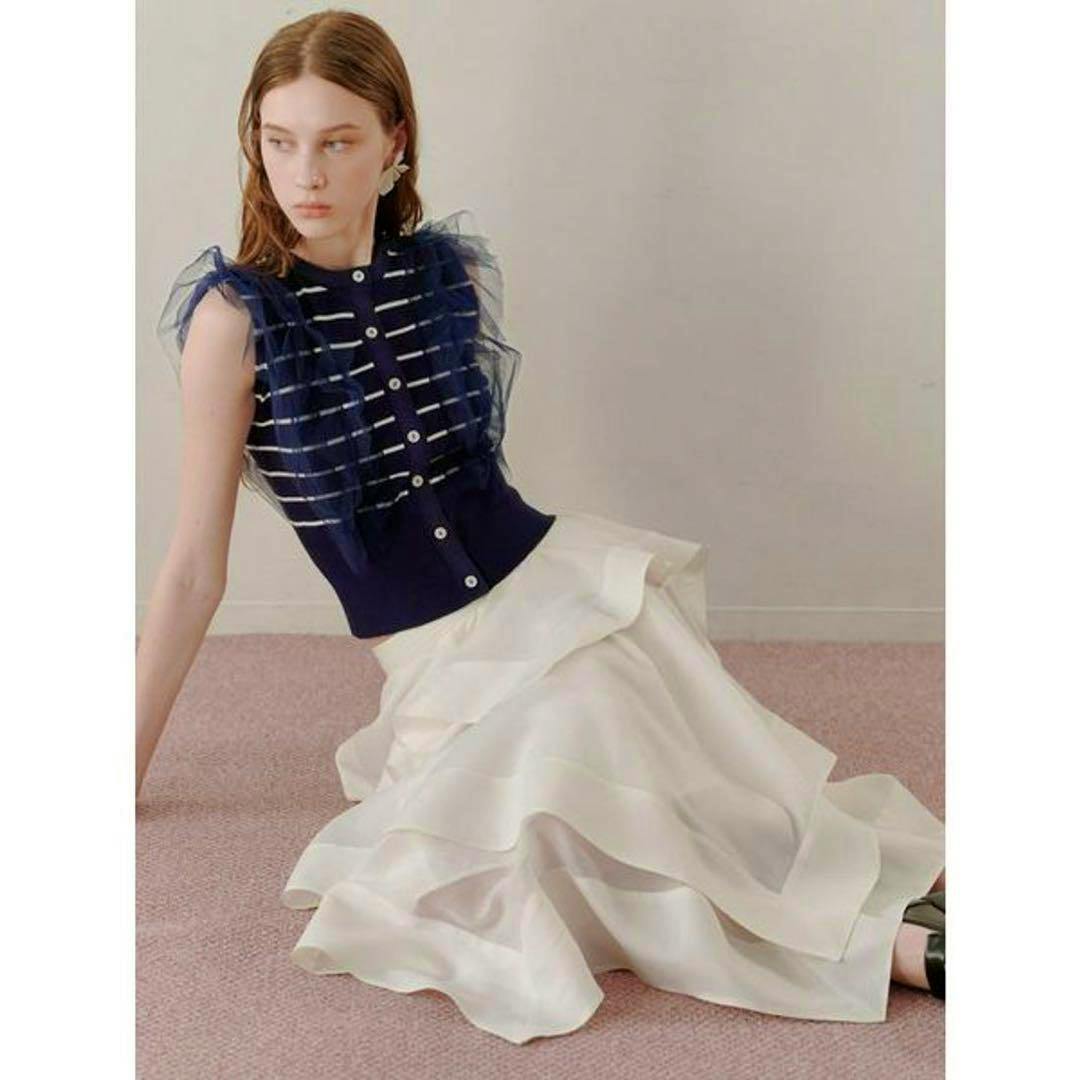 A seated model wearing the SNIDEL white tiered skirt.