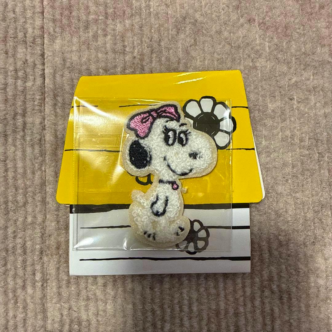 Shaggy embroidered sticker of Belle (Snoopy) with a pink bow in plastic packaging on a yellow and white backing.