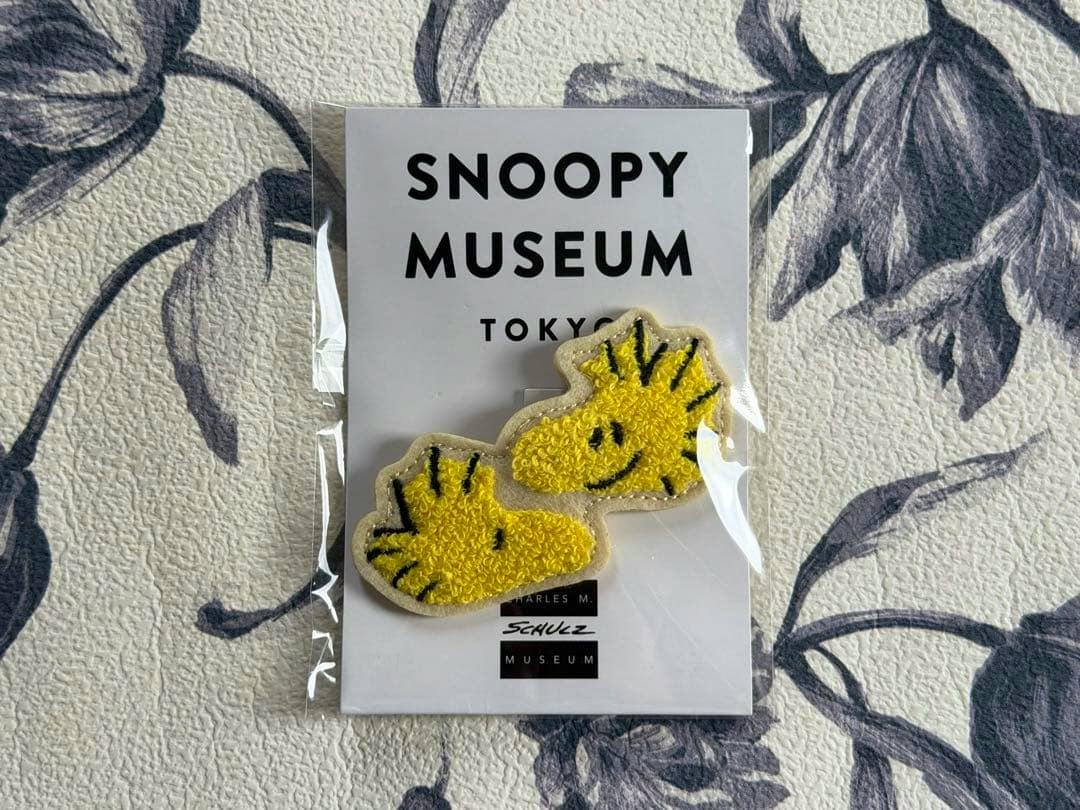 Packaged Snoopy Museum Tokyo backing card showing a yellow embroidered Woodstock badge.