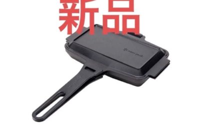 Closed black sandwich skillet with handle shown from an angle.