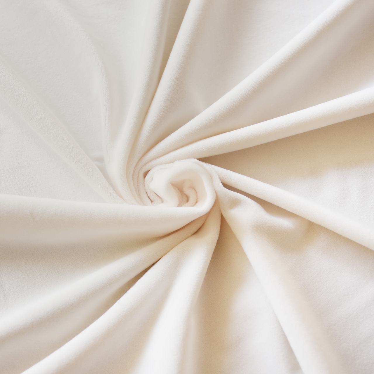 Off-white soft pile polyester fabric for plush toys arranged in a swirl showing texture.