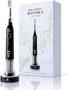 Front view of the Soladay Rhythm 3 sonic vibration electric toothbrush in piano black standing next to its retail box on a charging base.