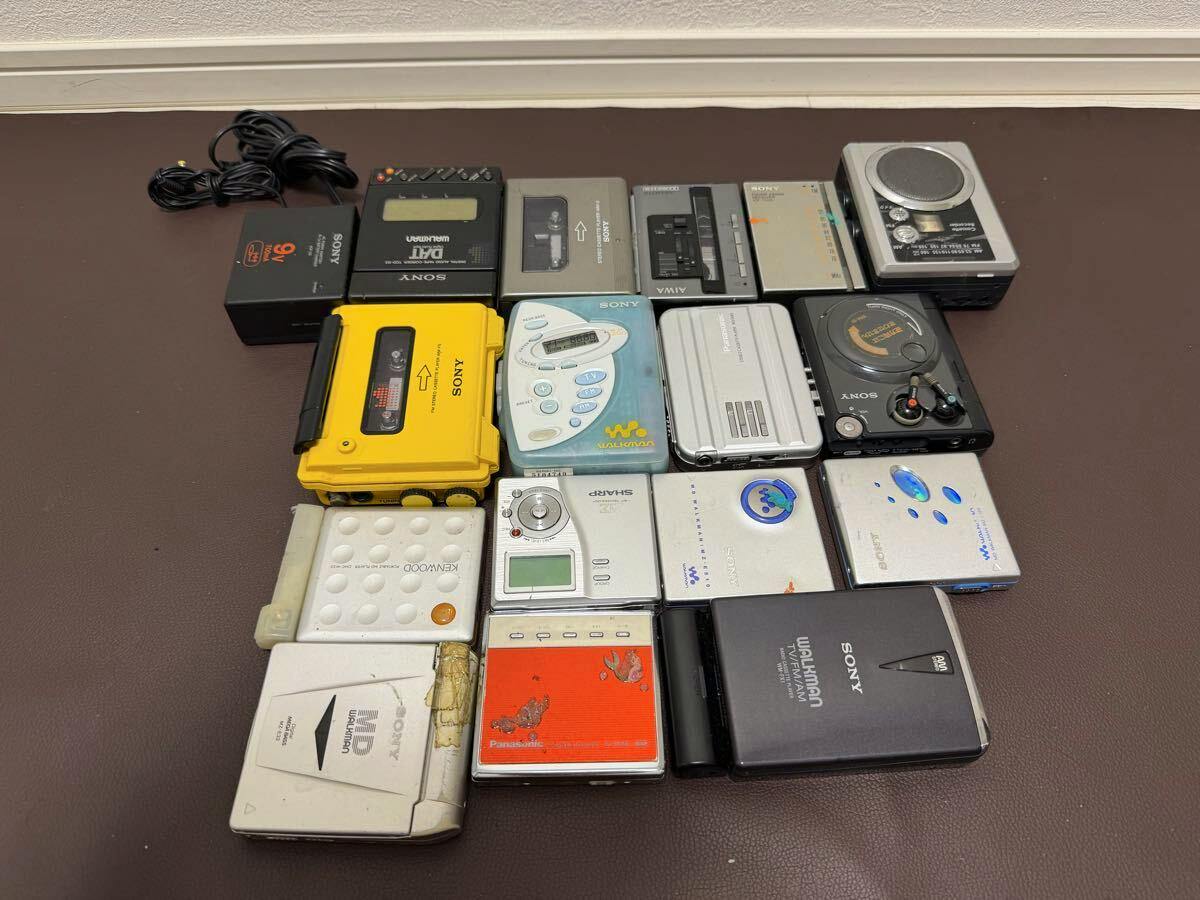 Multiple vintage portable cassette players and Walkman-style devices arranged on a brown surface.