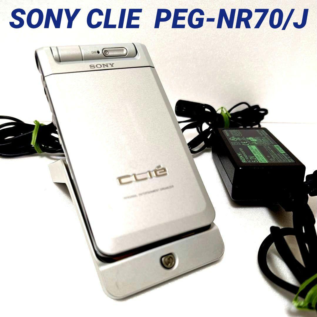 Silver Sony CLIE PEG-NR70/J handheld device on a charging cradle with an AC adapter visible.