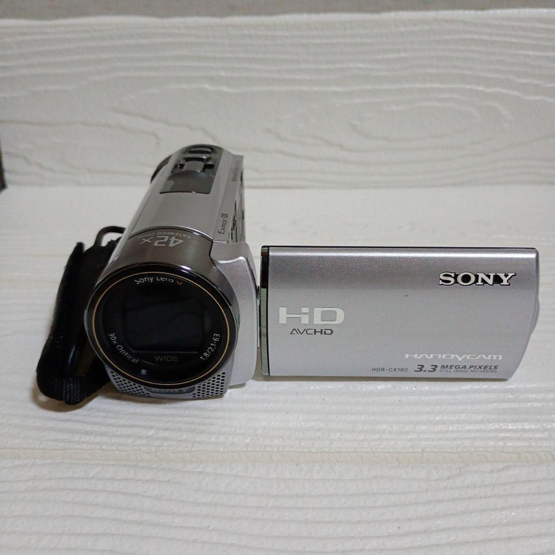 Front view of the silver Sony HDR-CX180 video recorder with its flip-out LCD screen open.