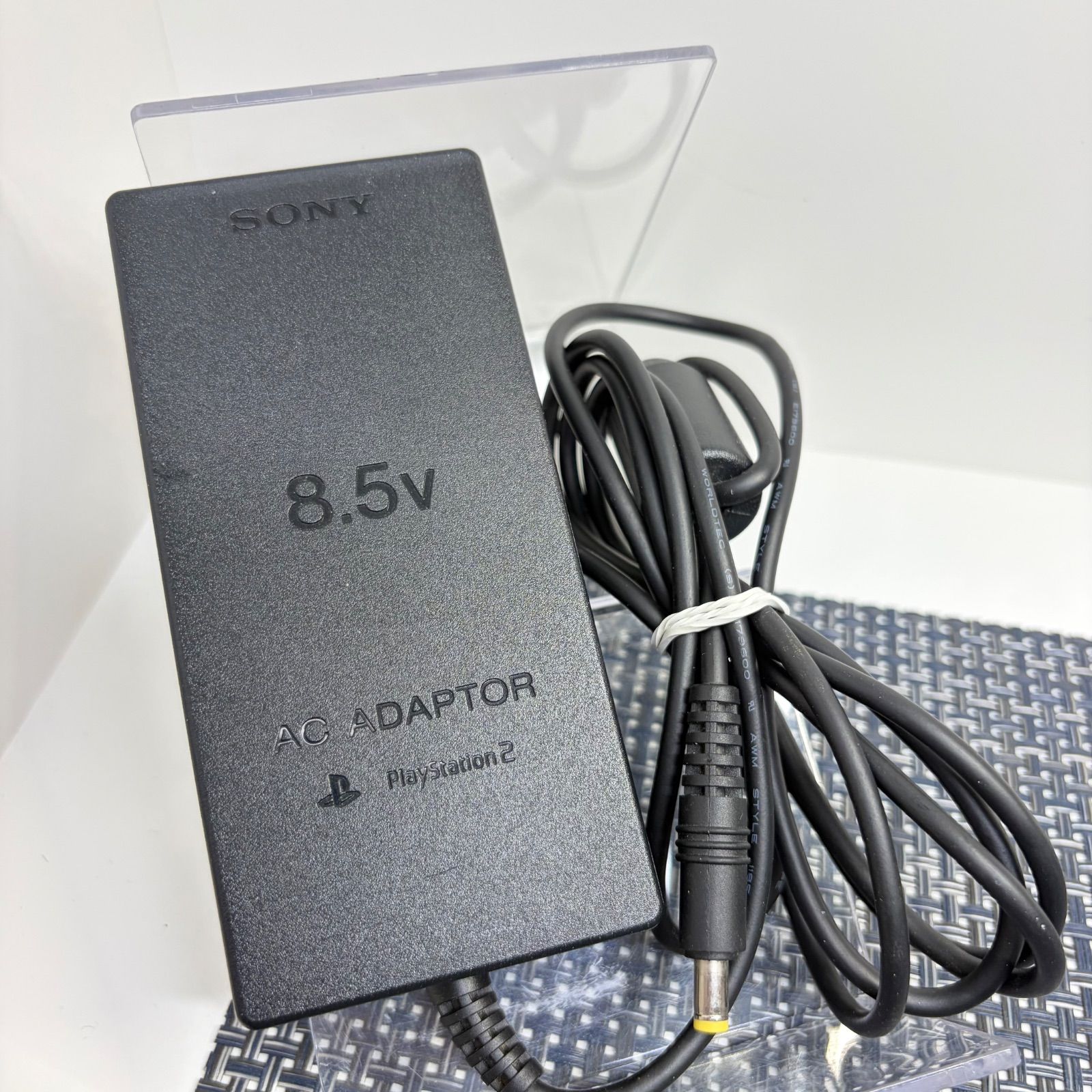Sony PlayStation 2 AC adapter (8.5V) with attached cable and barrel connector shown on a white surface.