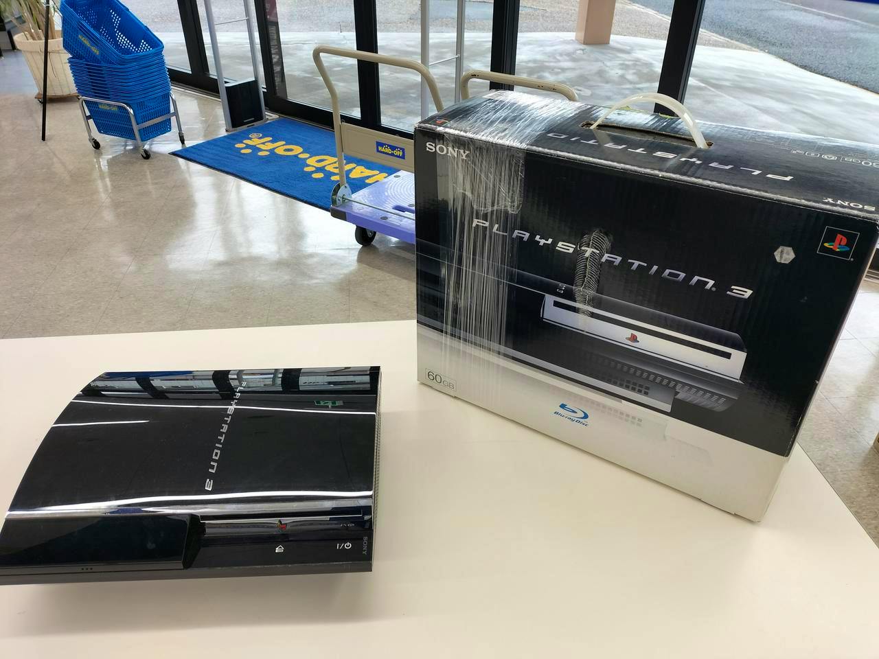 A Sony PlayStation 3 console shown on a table next to its boxed packaging.