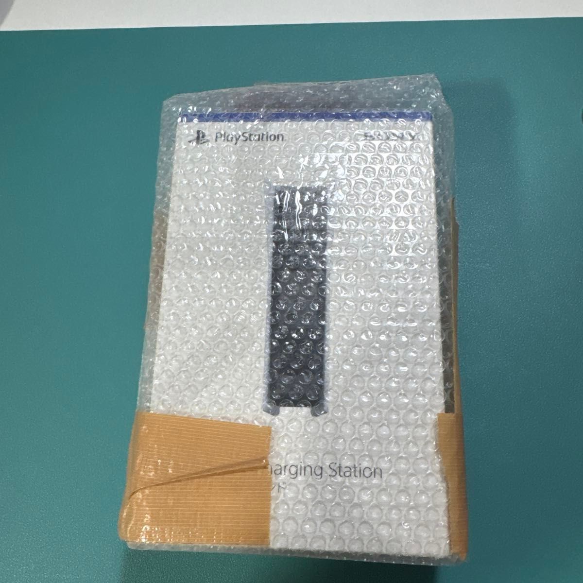 Front of boxed Sony PlayStation DualSense Charging Station wrapped in bubble wrap and taped packaging.