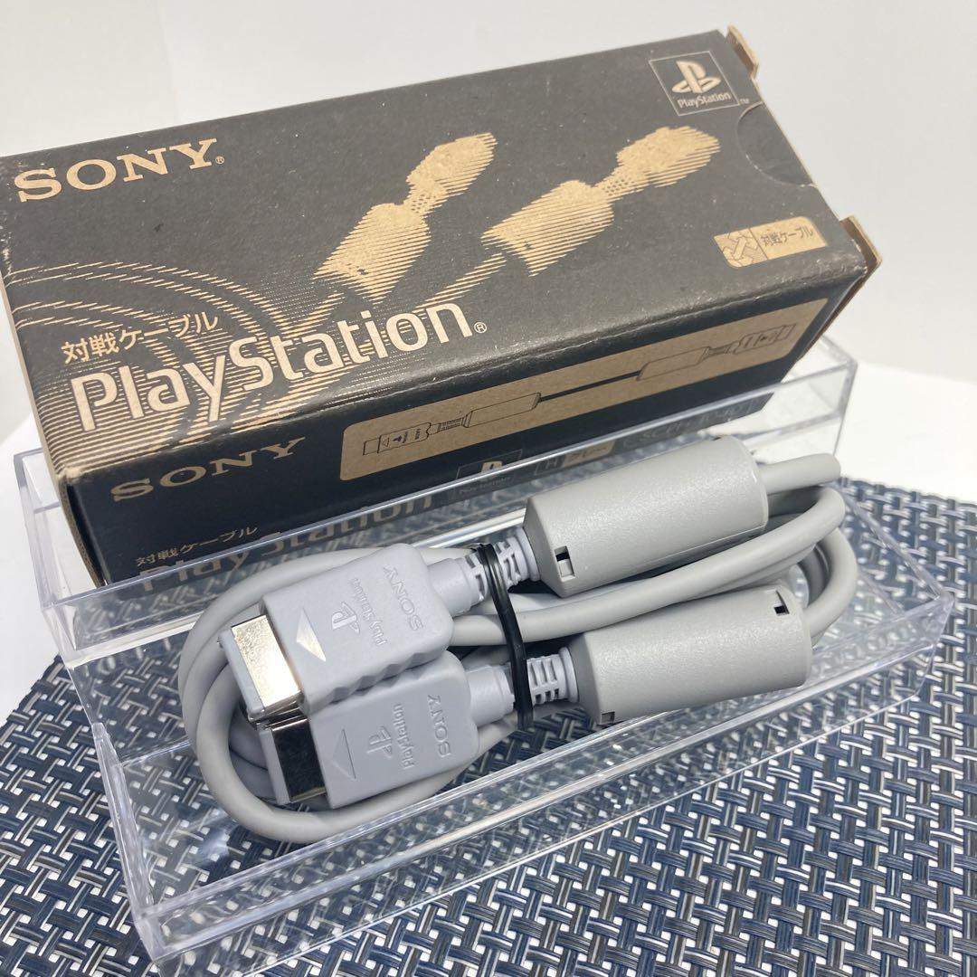 A Sony PlayStation SCPH-1040 link cable coiled in front of its original PlayStation box.