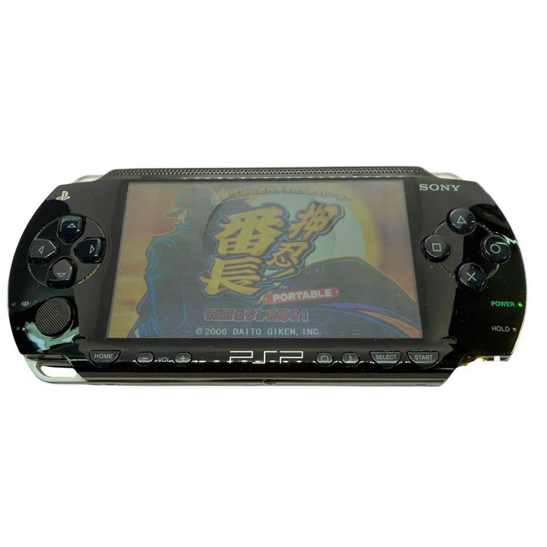 Front view of a piano-black PSP-1001 handheld game console with a game displayed on its screen and front buttons visible.